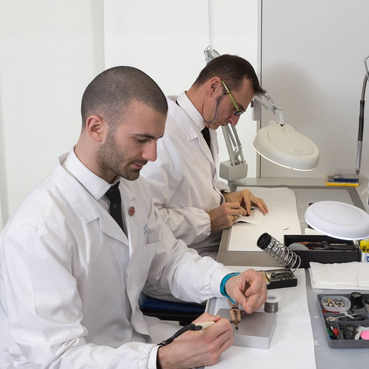 Due tecnici Centriudito al banco di laboratorio mentre intervengono su un apparecchio acustico