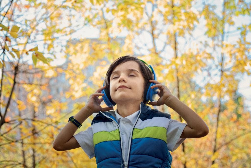Bambino che ascolta con le cuffie, all'aperto
